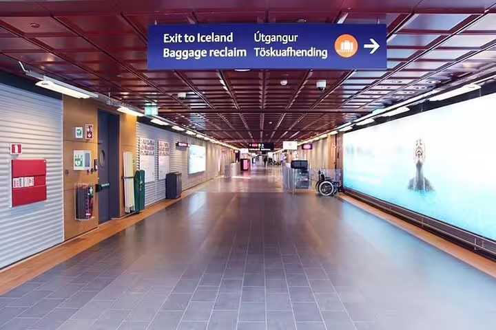 Empty corridor at Keflavik Airport with signs for baggage reclaim and exit to Iceland