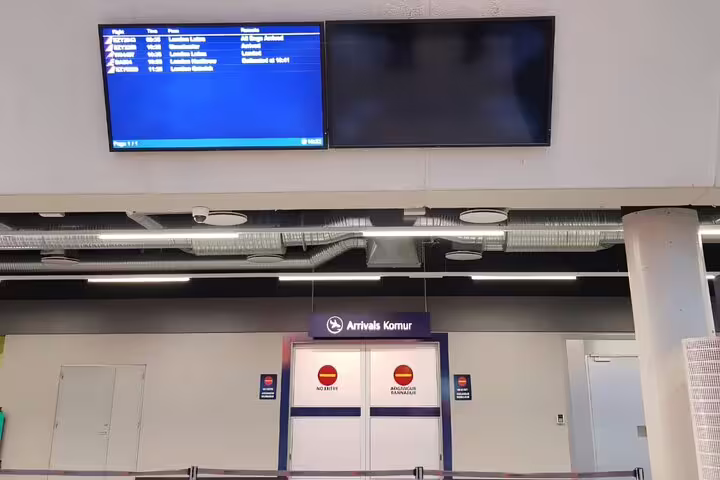 Arrivals hall at Keflavik Airport Iceland with flight information board and Komur sign