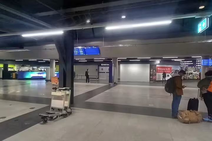 Quiet Keflavik Airport arrivals hall with luggage carts and passengers near Welcome to H1 sign