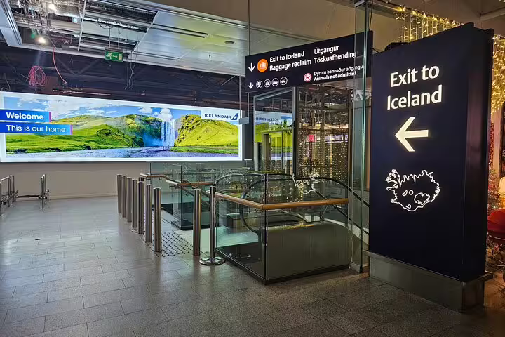 Exit to Iceland sign at Keflavik Airport arrivals hall with Icelandair welcome screen