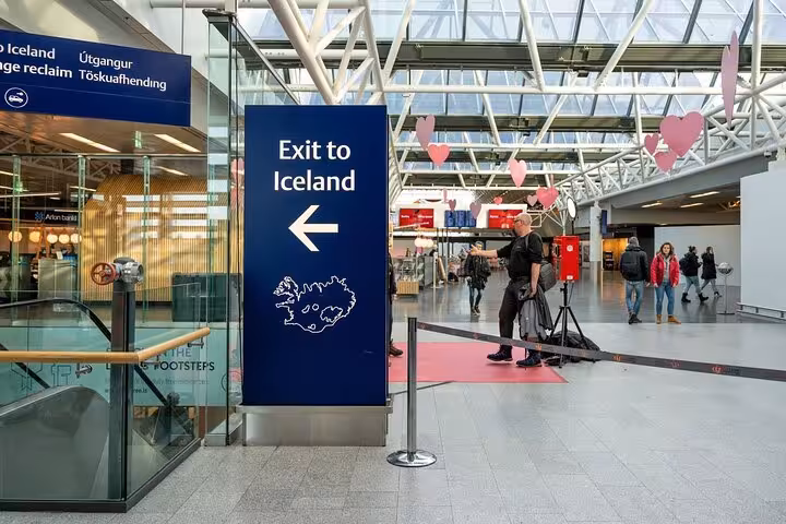 Exit to Iceland sign at Keflavik Airport terminal with travelers in background