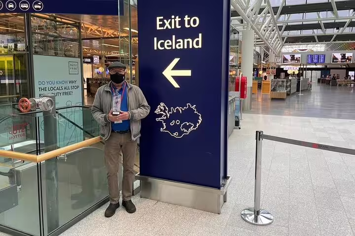Traveler standing next to Exit to Iceland sign at Keflavik Airport terminal