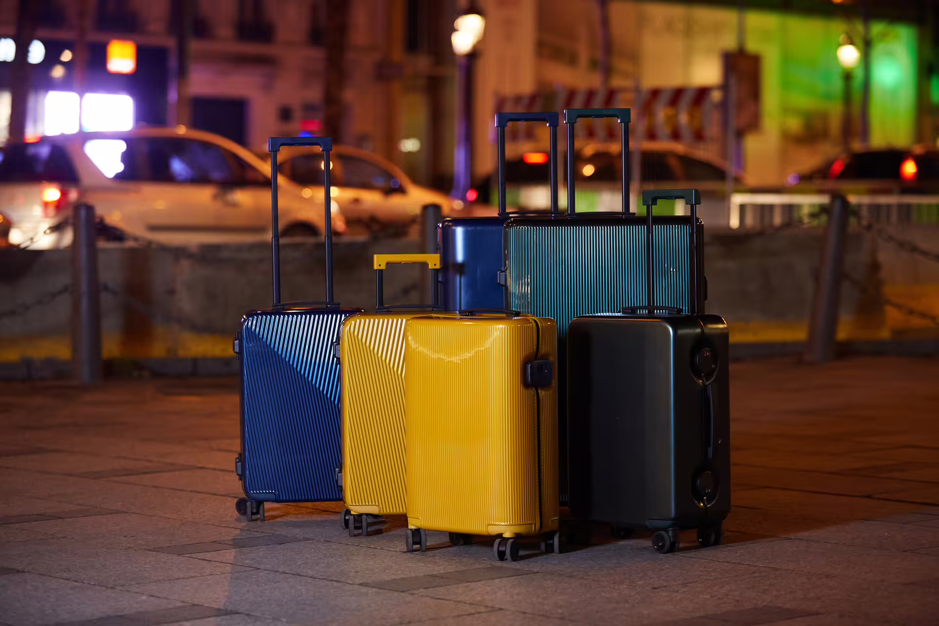 Colorful hardshell luggage suitcases lined up on a city street at night