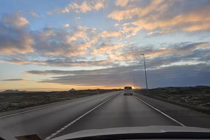 View from car driving on Icelandic highway toward Reykjavik at sunset with dramatic cloudy sky