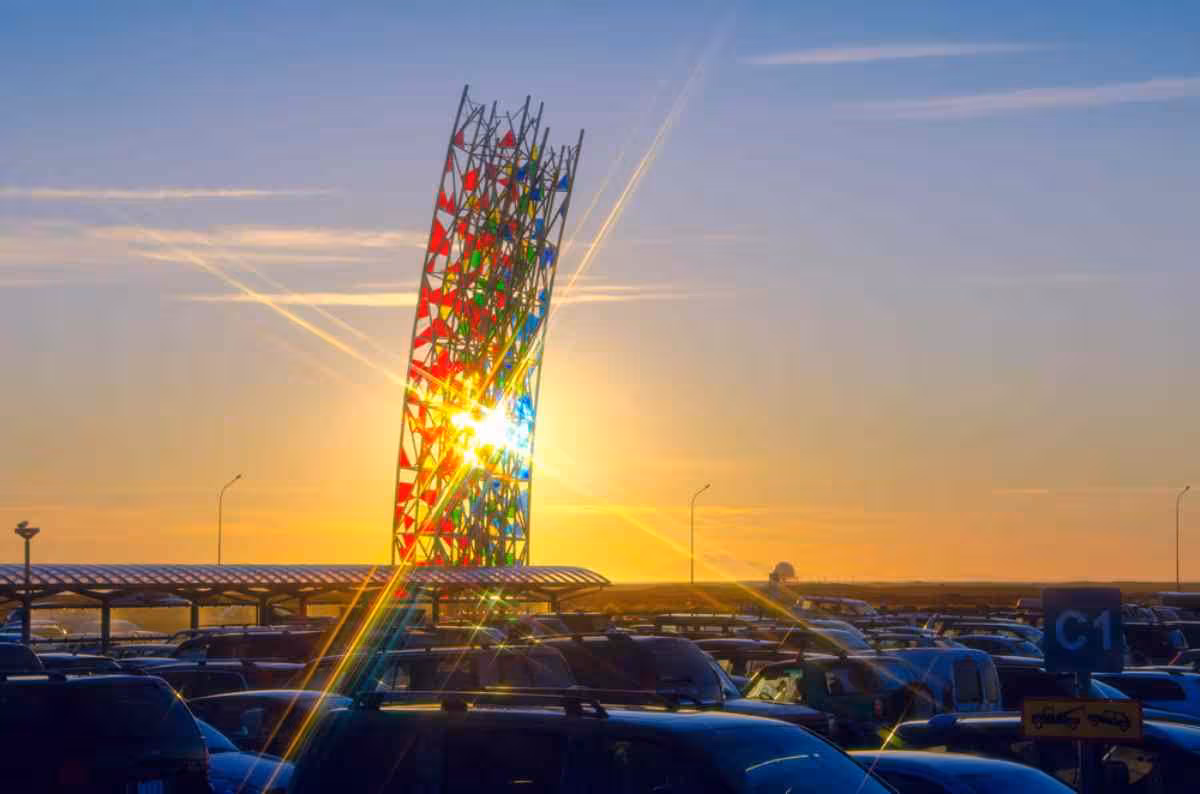 Colorful geometric sculpture tower at Keflavik Airport parking lot during golden sunset
