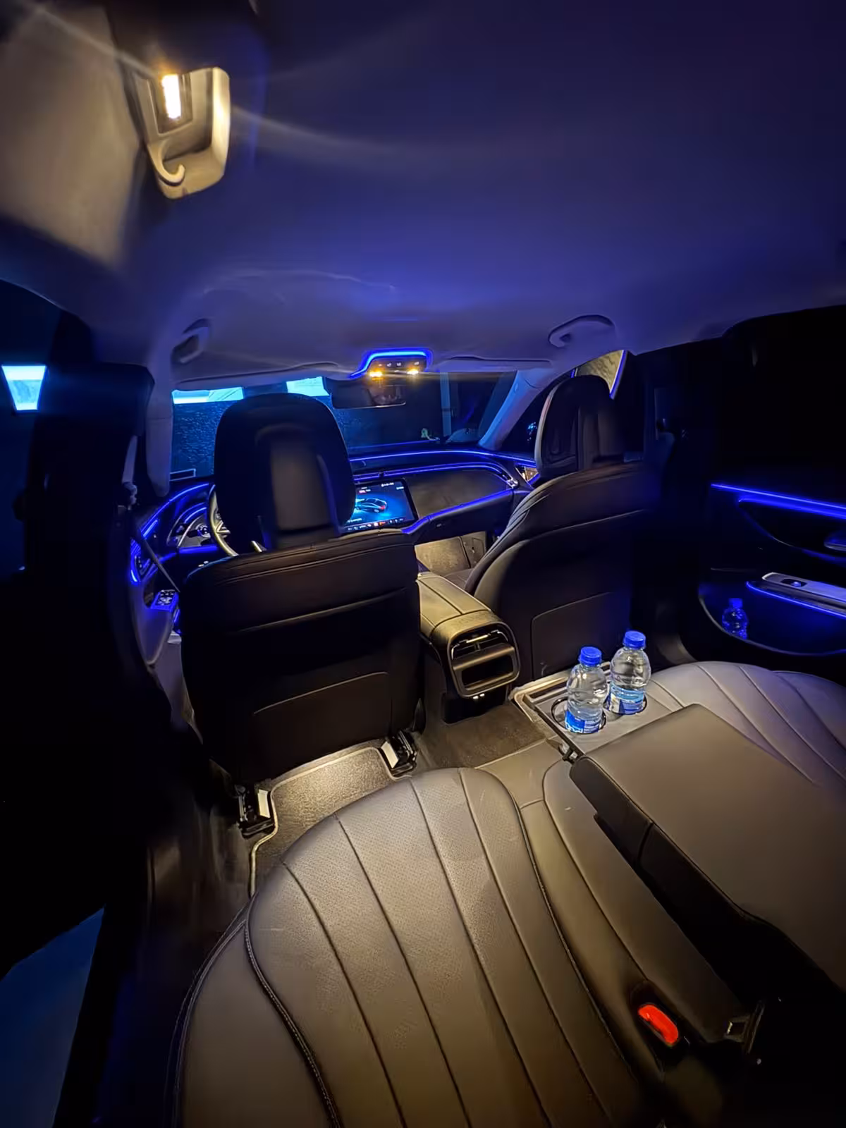 Luxury sedan interior with blue ambient lighting and water bottles for Keflavik Airport transfer