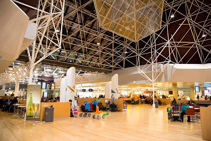 Keflavik Airport terminal interior with seating areas, shops, and travelers near departure gates
