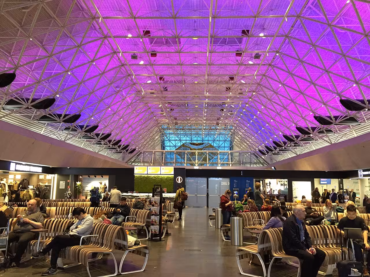 Keflavik Airport terminal waiting area with purple lit geometric ceiling and travelers seated