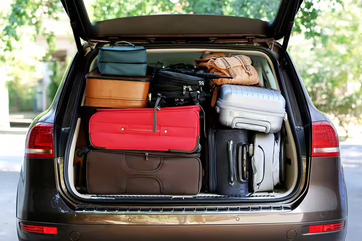 Car trunk fully packed with multiple suitcases and luggage bags for airport transfer