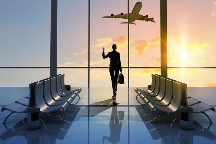 Business traveler waving at airplane from Keflavik Airport terminal at sunset
