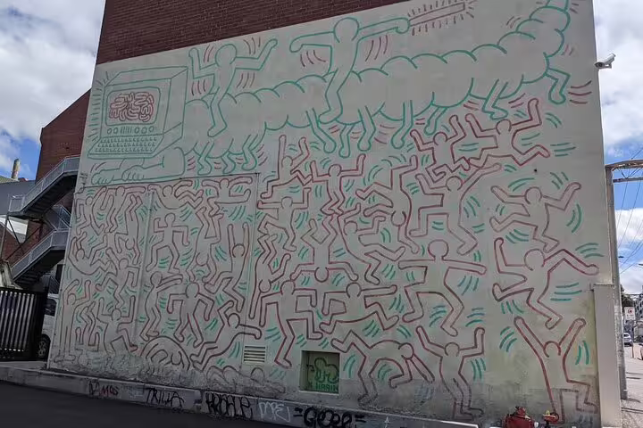 Keith Haring-style street art mural with bold outline figures on Melbourne building wall