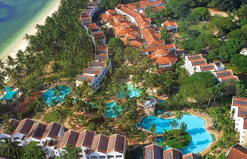 Aerial view of a luxury Kenya Coast golf tour resort with pools, palm trees, and beachfront villas