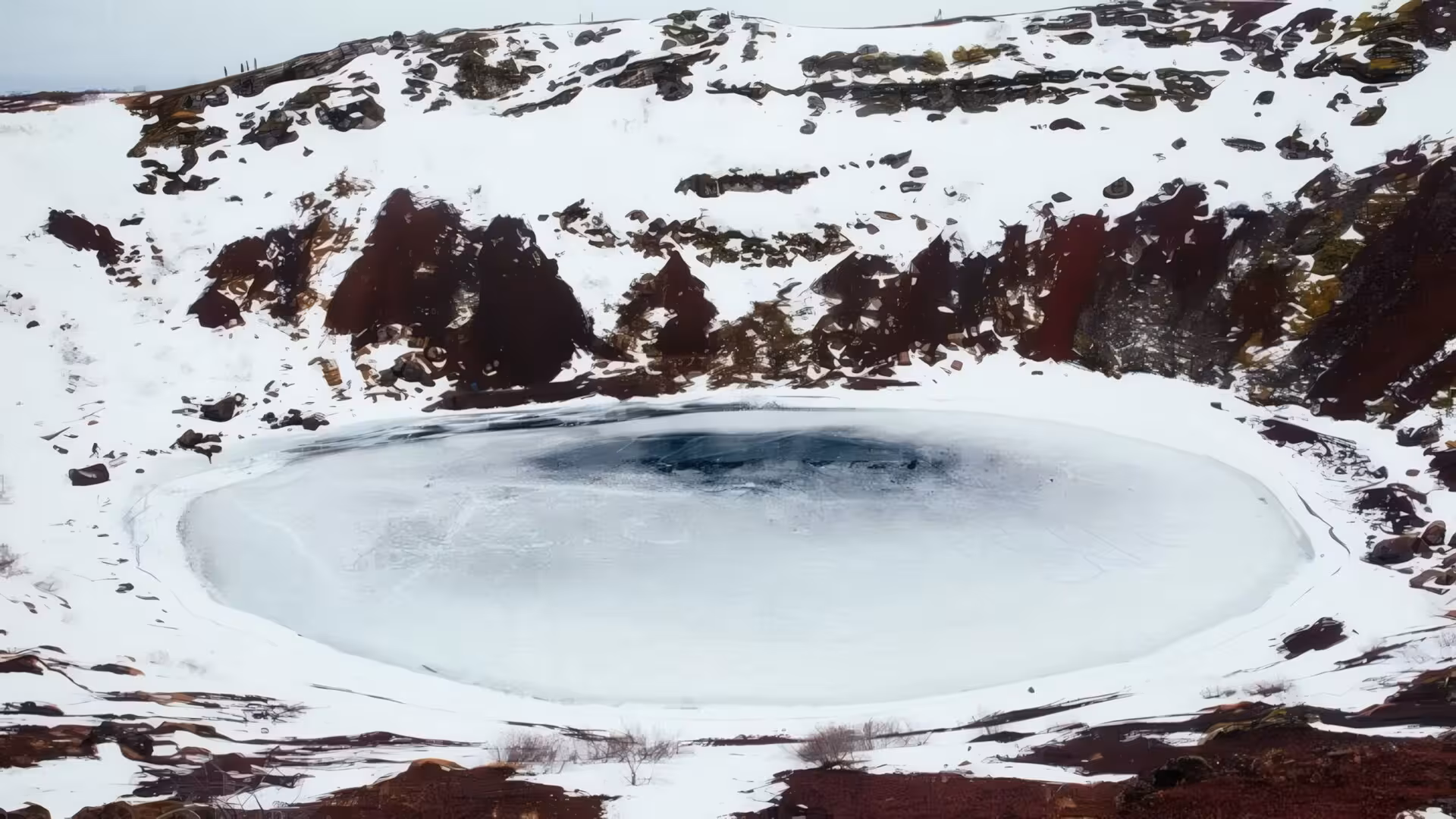 Frozen volcanic crater lake Kerid surrounded by red rocks and snow, Iceland Golden Circle