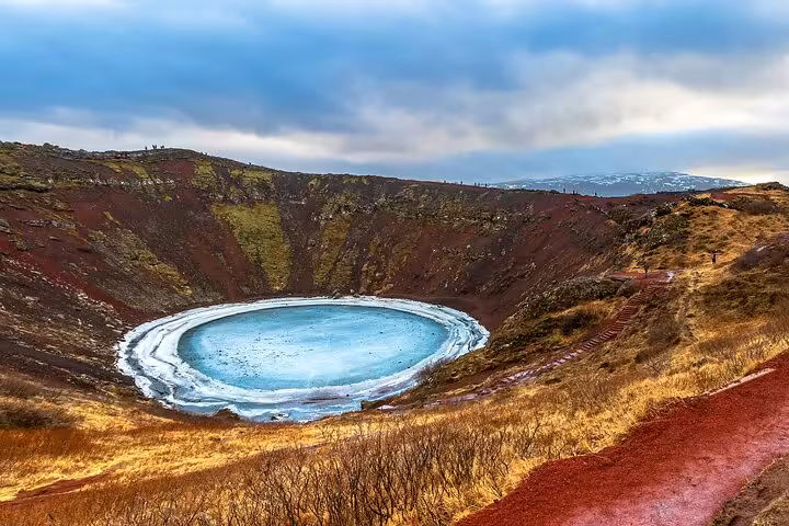 Kerið volcanic crater lake with turquoise frozen water and red volcanic walls, Iceland Golden Circle