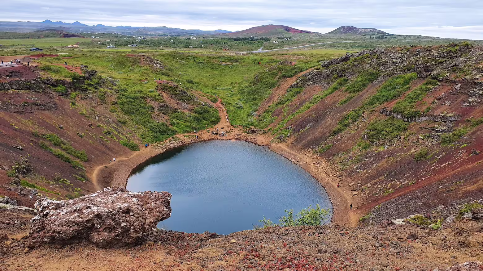 Kerid volcanic crater lake with red rocky walls and green slopes on Iceland's Golden Circle route