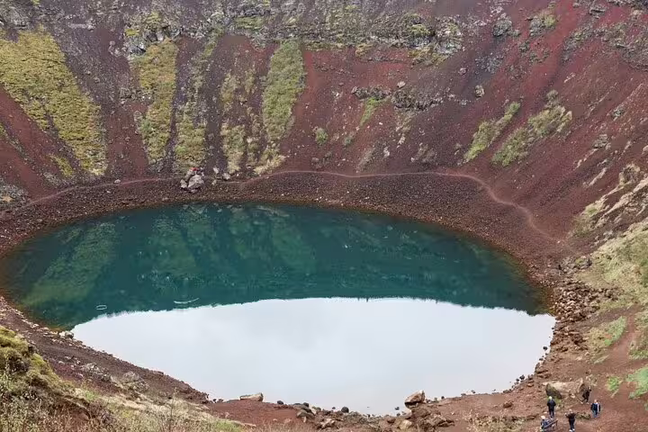 Kerid volcanic crater lake with vivid teal water surrounded by red lava rock walls, Golden Circle Iceland