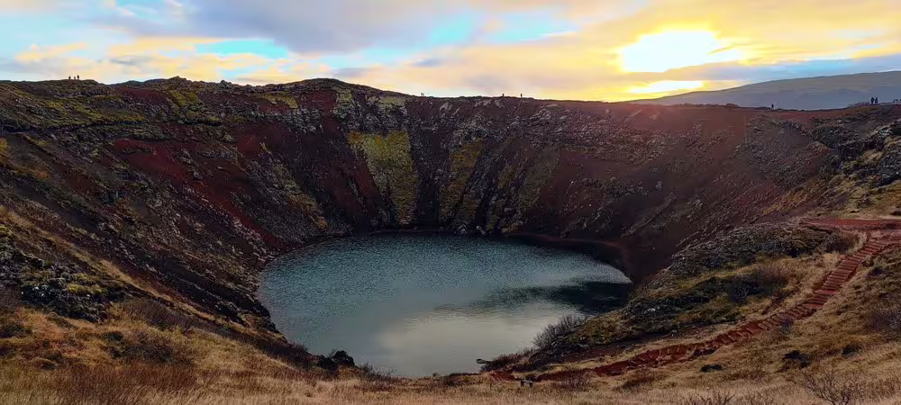 Kerid volcanic crater lake with red walls and calm blue water at sunset, Iceland Golden Circle