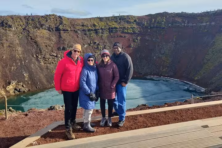 Four tourists posing at Kerid volcanic crater lake on Golden Circle tour in Iceland