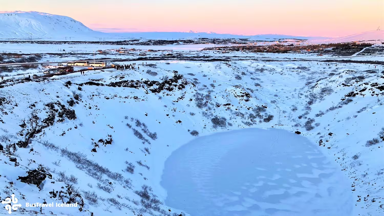 Aerial view of snow-covered Kerid volcanic crater with frozen lake in Iceland during winter