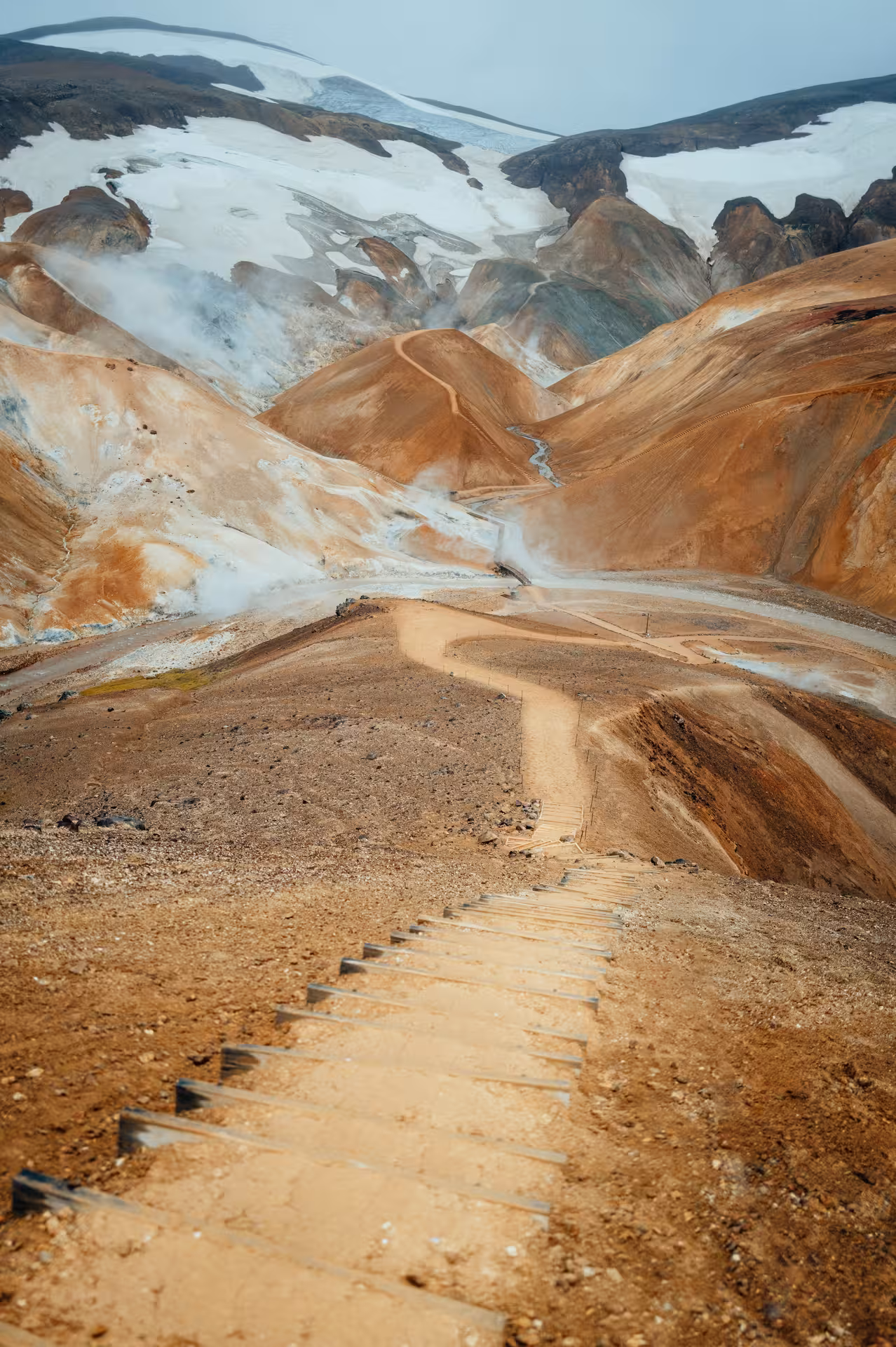 Wooden steps descending into Kerlingarfjoll geothermal highlands with colorful rhyolite mountains and steam vents