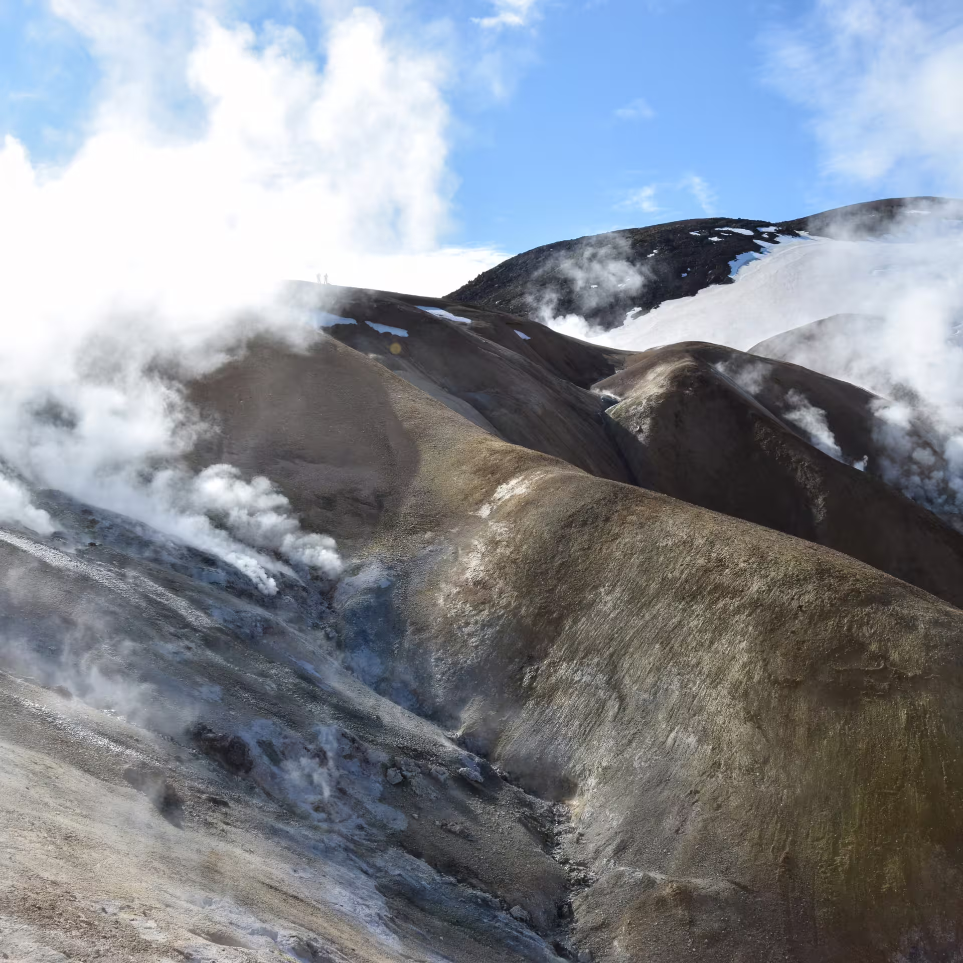Steaming geothermal vents rising from Kerlingarfjoll rhyolite mountains with snow patches on private jeep hiking day tour from Reykjavik