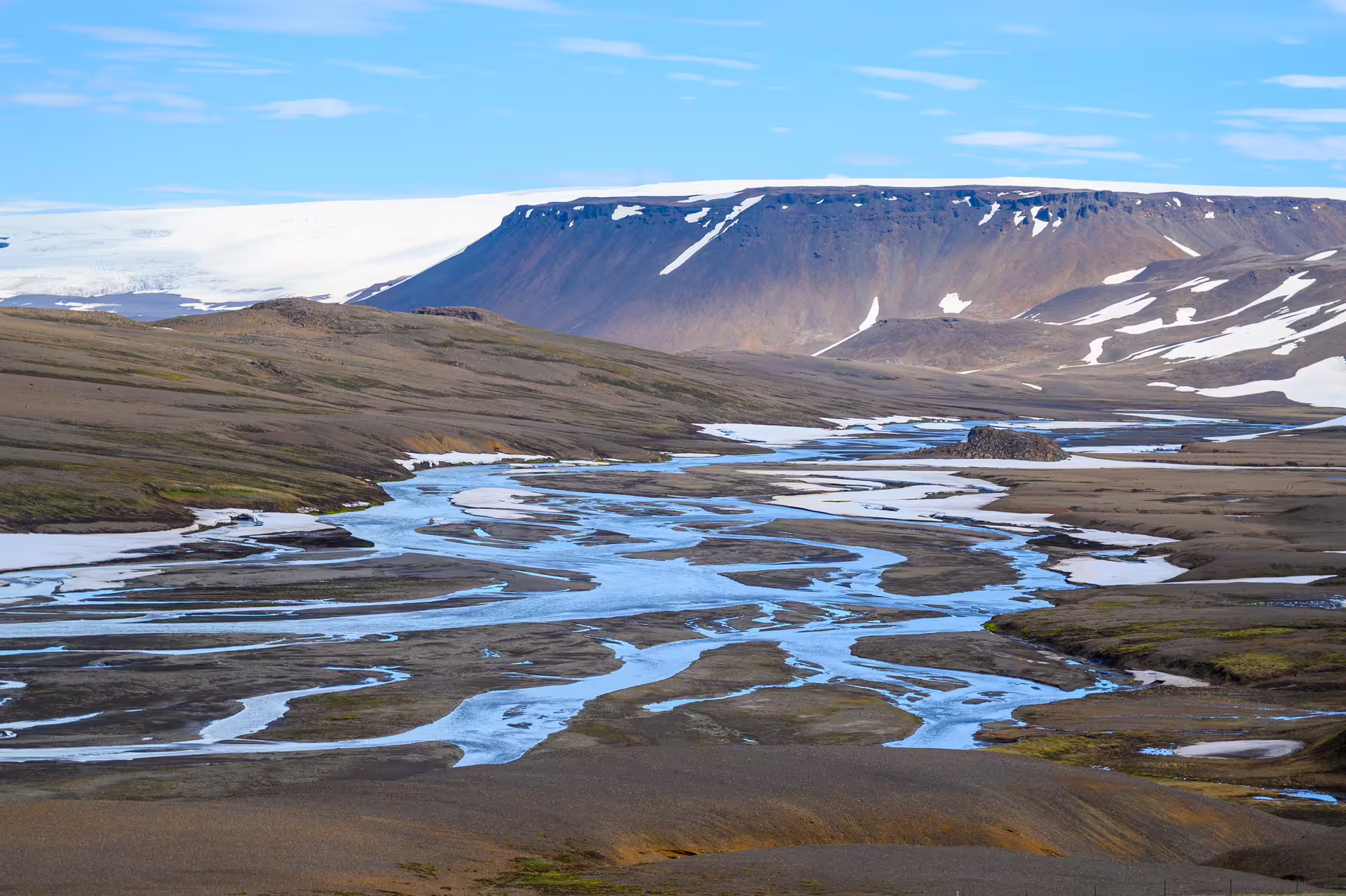 Braided glacial river flowing through Kerlingarfjoll highlands with snow-capped flat-top mountains in background