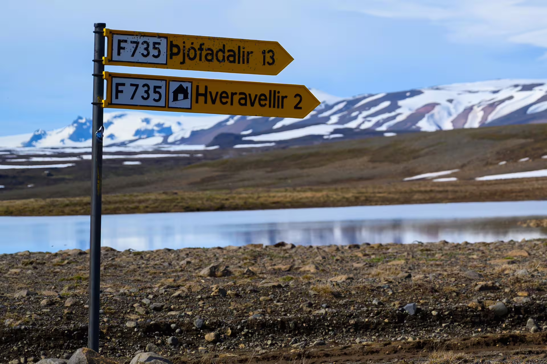 Yellow F735 road signs pointing to Þjófadalir and Hveravellir with snow-capped mountains in Iceland highlands