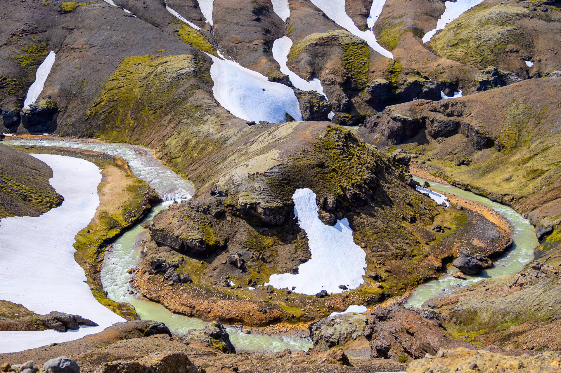 Turquoise glacial river winding through snow-patched volcanic highlands of Kerlingarfjoll, Iceland