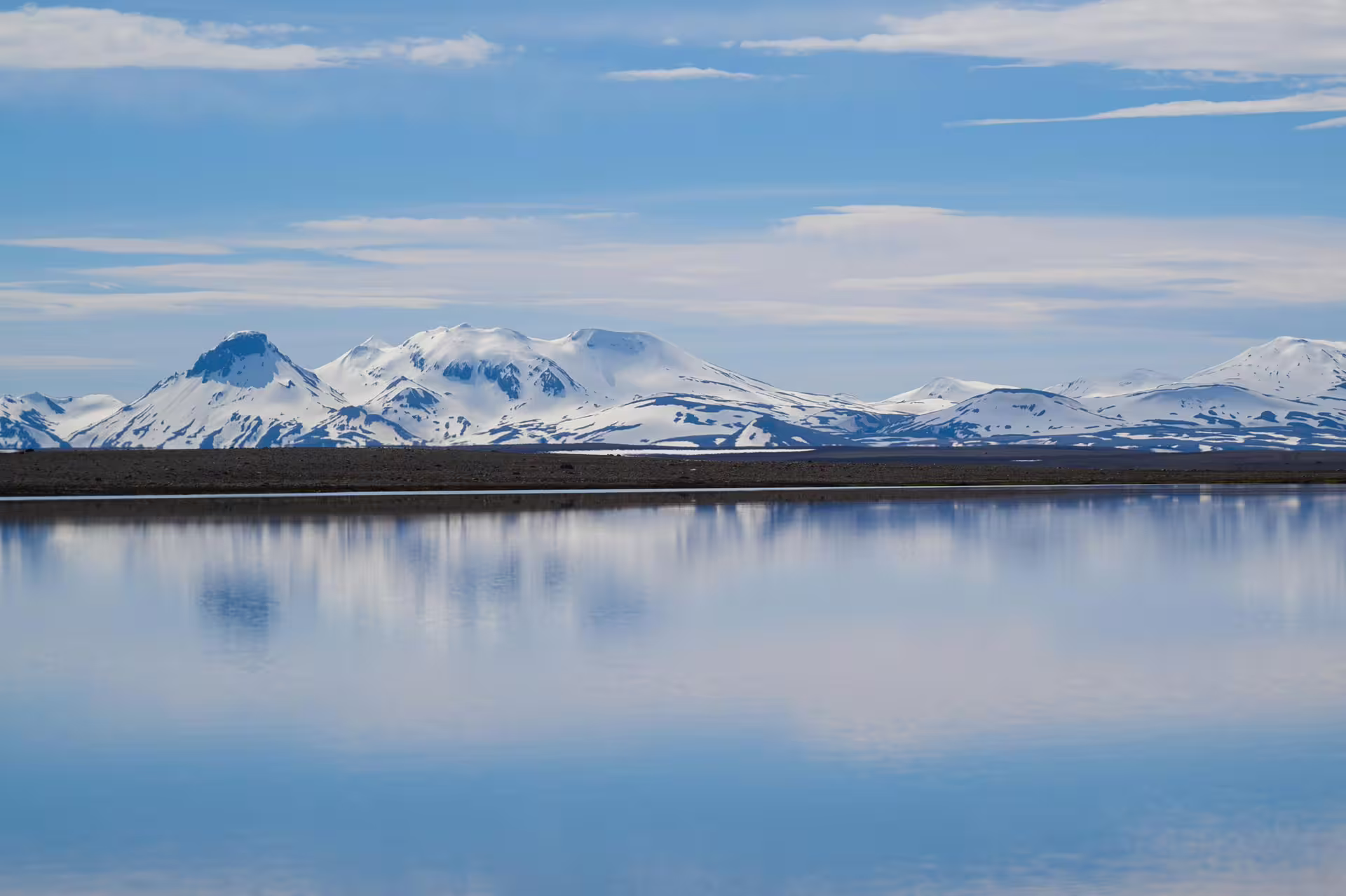 Snow-capped Kerlingarfjoll mountains reflecting in a calm glacial lake under blue skies, Iceland Highlands