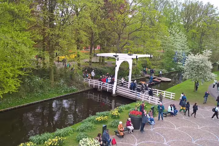 Keukenhof canal bridge with spring blooms and visitors, part of small-group tulip tour from Amsterdam