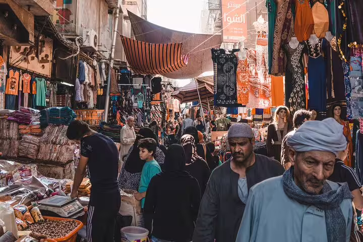 Crowded Khan el-Khalili bazaar lane in Cairo with textiles and shoppers on Citadel and museum tour
