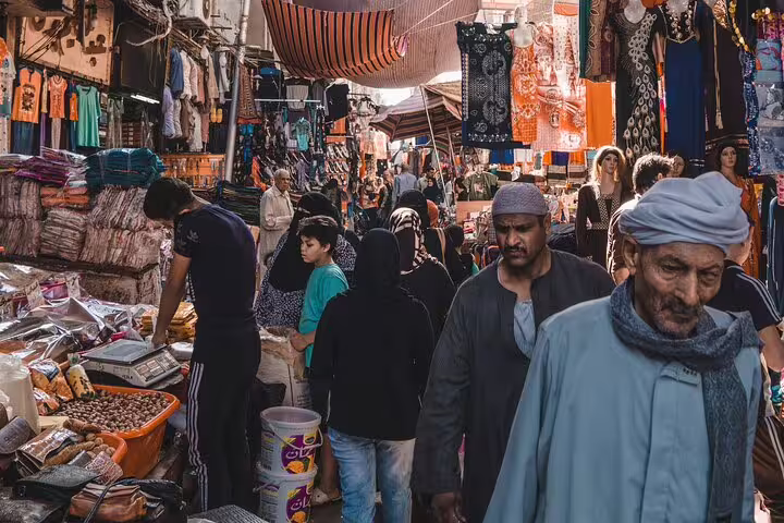 Crowded Khan El Khalili market lane with textiles and locals, authentic shopping on private Old Cairo tour