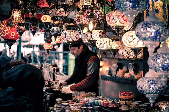 Vendor beneath colorful mosaic lamps at Khan el-Khalili, browsing souvenirs on a Medieval Cairo bazaar tour