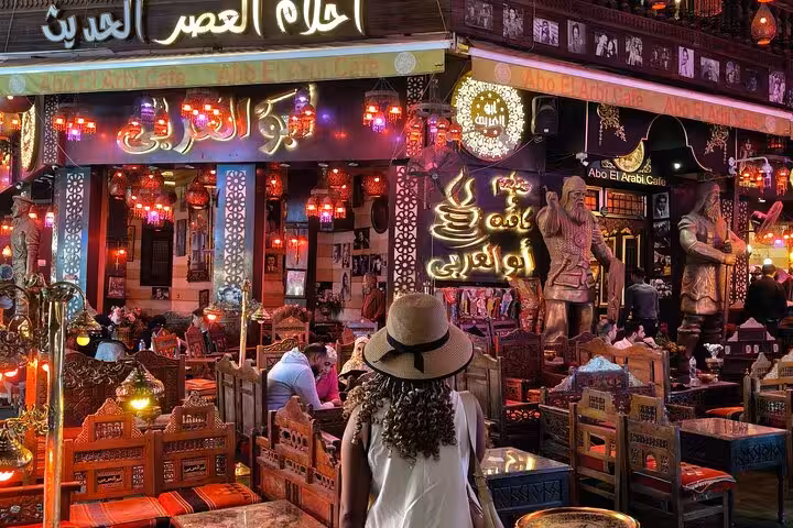 Khan El Khalili Bazaar night scene with lantern-lit cafe and traveler, part of VIP Cairo night tour on Al Muizz Street