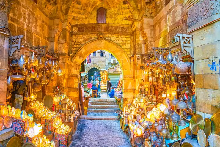 Glowing brass lanterns and souvenirs under an old archway at Khan El Khalili, Islamic Cairo walking tour