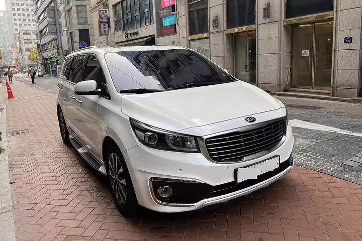 White Kia Carnival minivan parked on city street for luxury private transfer Abu Dhabi to AUH Airport