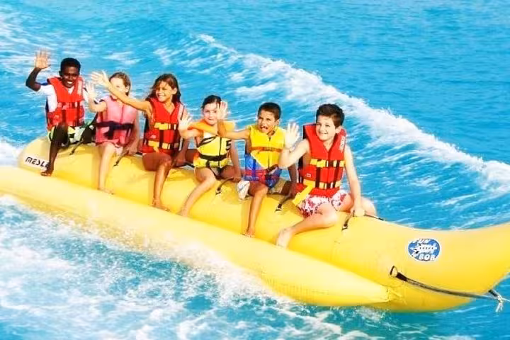 Kids waving on a banana boat ride in the Red Sea, fun water activity on Super Giftun Island excursion Hurghada