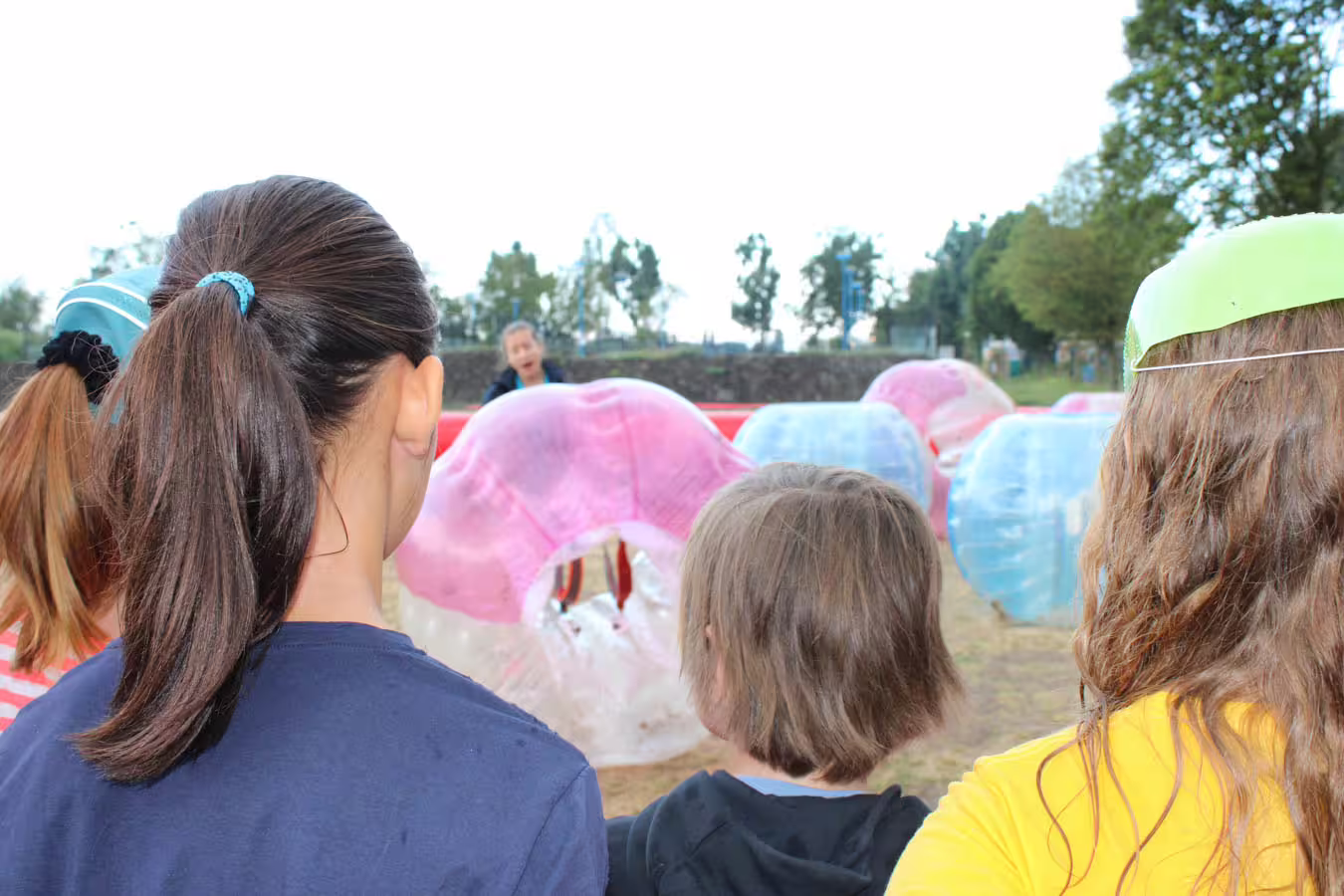 Kids watching bubble football game in Weesp with colorful inflatable suits, perfect family and group outing