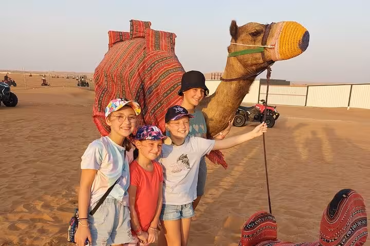Children enjoying a fun camel interaction during an Abu Dhabi desert safari camel ride experience at sunset