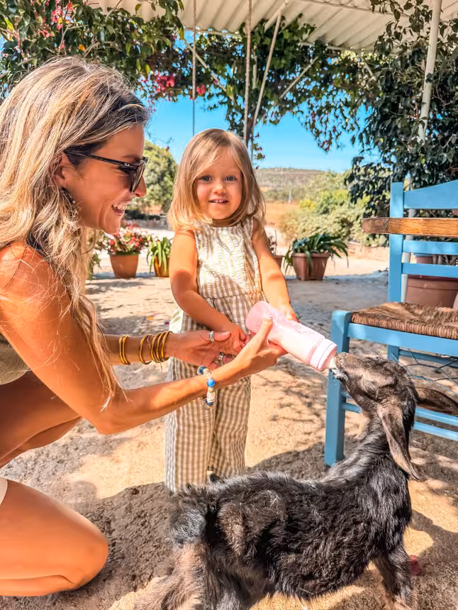 Mom and toddler bottle-feeding a baby goat at a family-friendly Kids First farm animal encounter tour