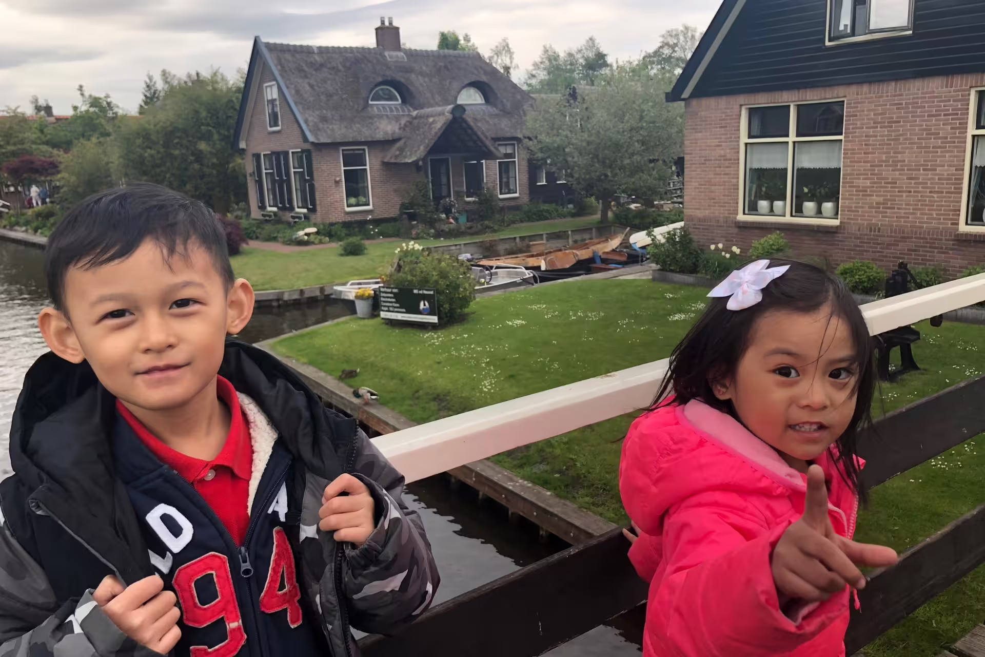 Kids on Giethoorn canal bridge with thatched cottages, part of Amsterdam to Giethoorn and Zaanse Schans tour