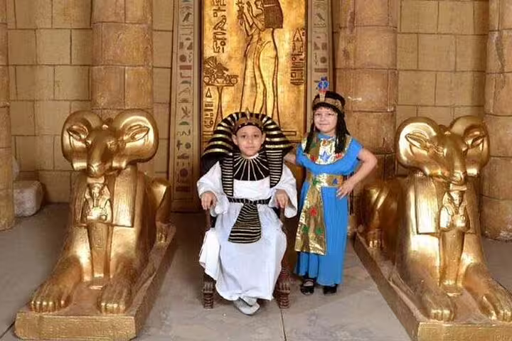 Kids in pharaoh and queen costumes beside golden sphinxes in a replica temple at Pharaonic Village private tour