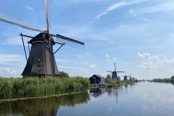 Classic Kinderdijk windmill beside calm canal, UNESCO sights on private tour from Rotterdam to Amsterdam