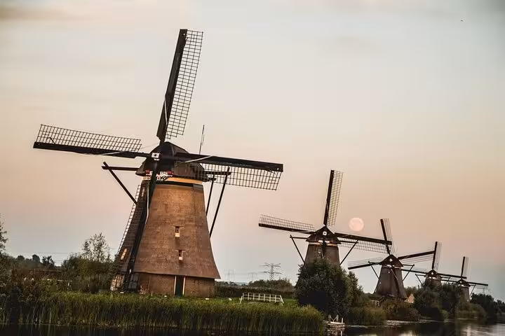 Iconic Kinderdijk windmills at sunset by the canal, must-see on a private day tour from Amsterdam to Delft and The Hague