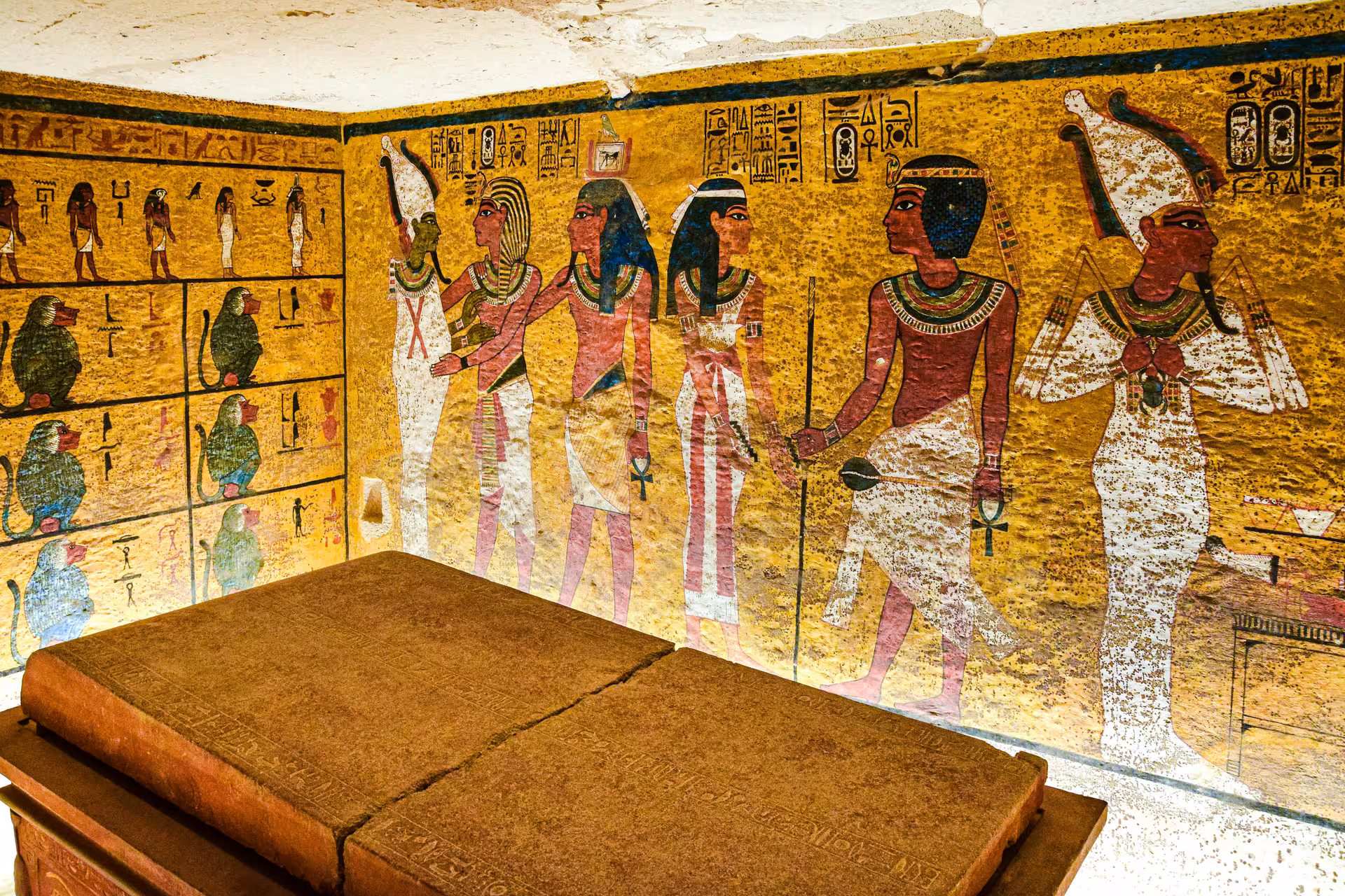 King Tut tomb burial chamber with golden wall paintings of Egyptian gods and hieroglyphics in Valley of the Kings