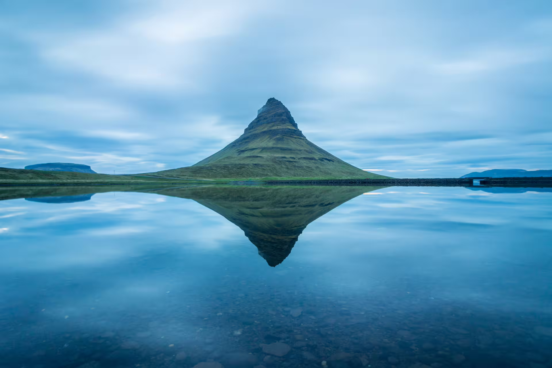Enchanting view of Kirkjufell during dawn, reflecting in the water.