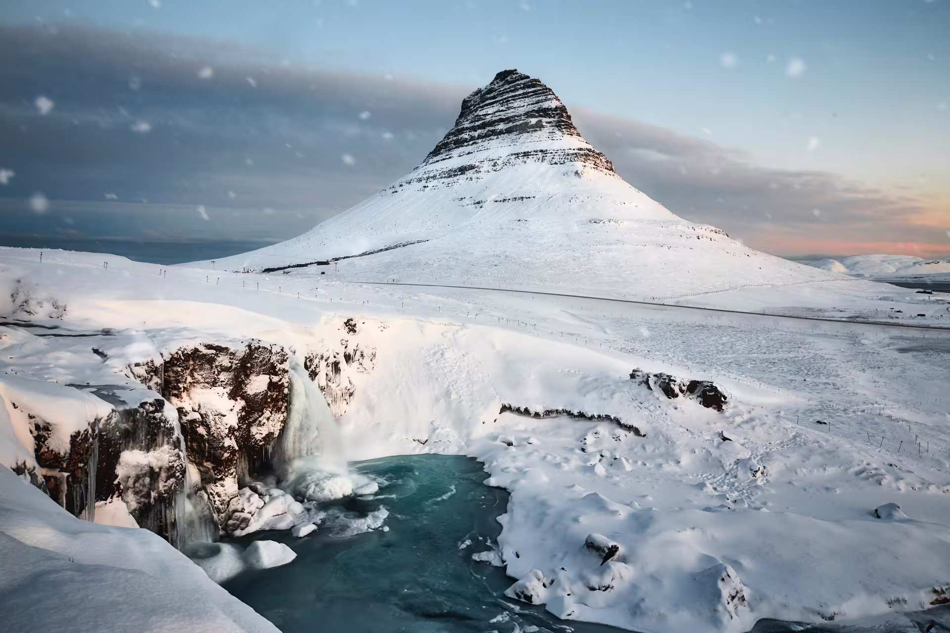 Snow-covered Kirkjufell mountain with frozen waterfall in Iceland winter landscape