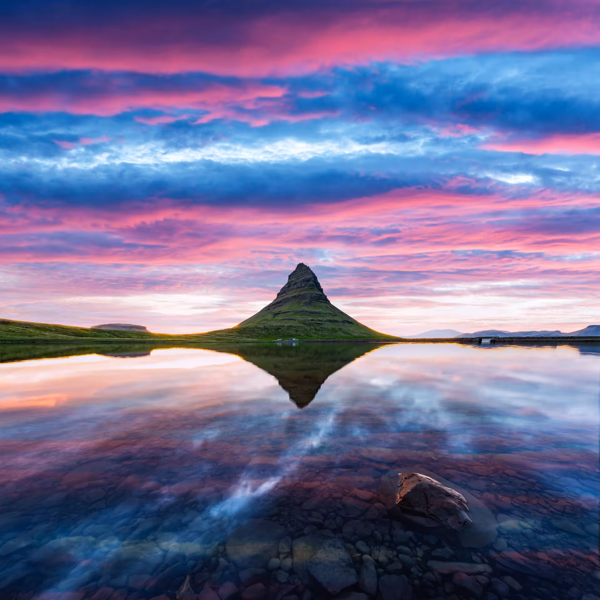 Kirkjufell mountain reflected in calm waters at vibrant pink and blue sunset, Snaefellsnes Peninsula, Iceland