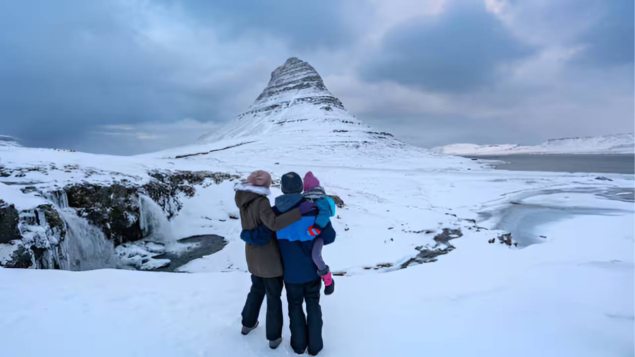 Family gazing at snow-covered Kirkjufell mountain on Snaefellsnes Peninsula in winter