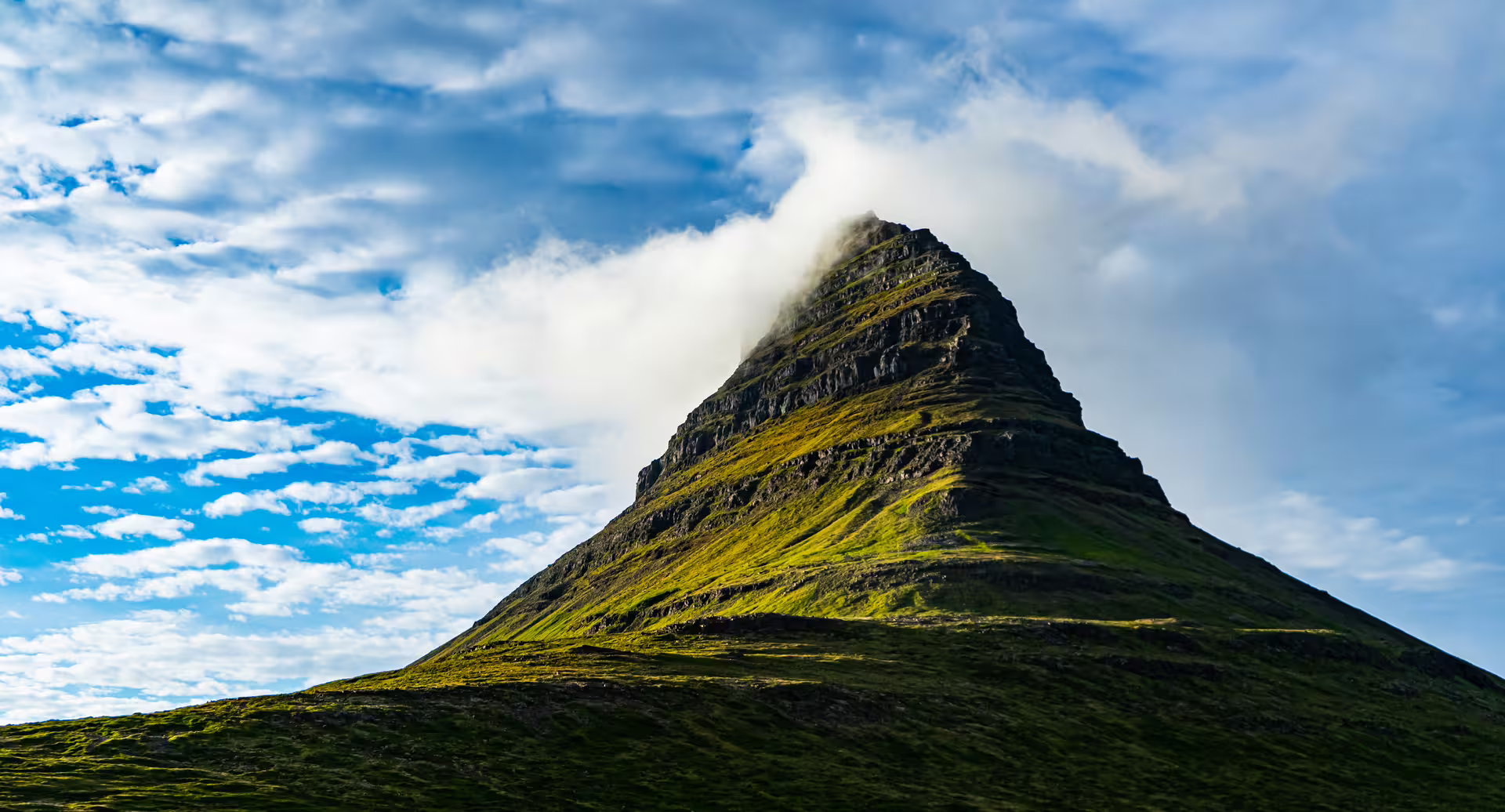 Kirkjufell mountain with green slopes and clouds at its peak, Snaefellsnes Peninsula, Iceland
